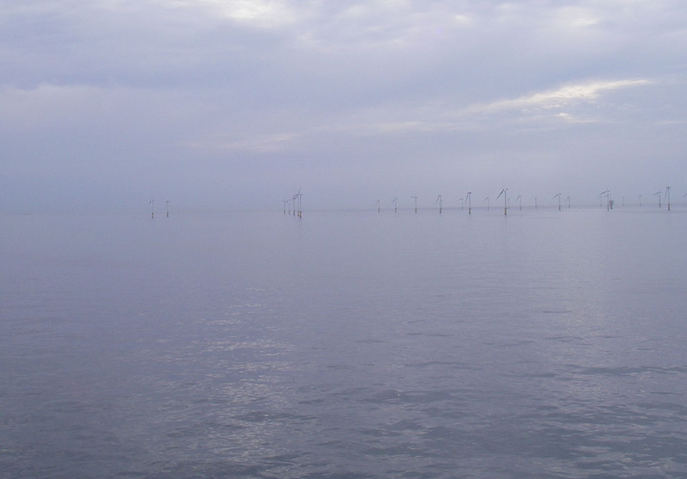 Vlak water en stilstaande windmolens voor de kust van IJmuiden